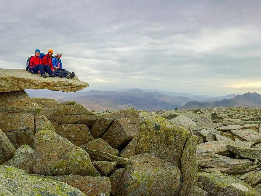 Group of people sitting on a rock ledge after scrambling