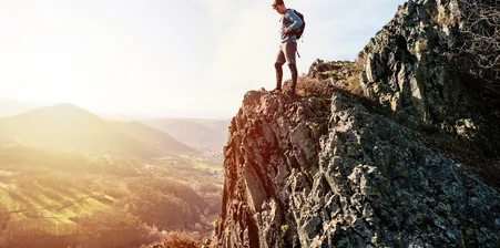 Adventurous young man looking over the edge of a rock face